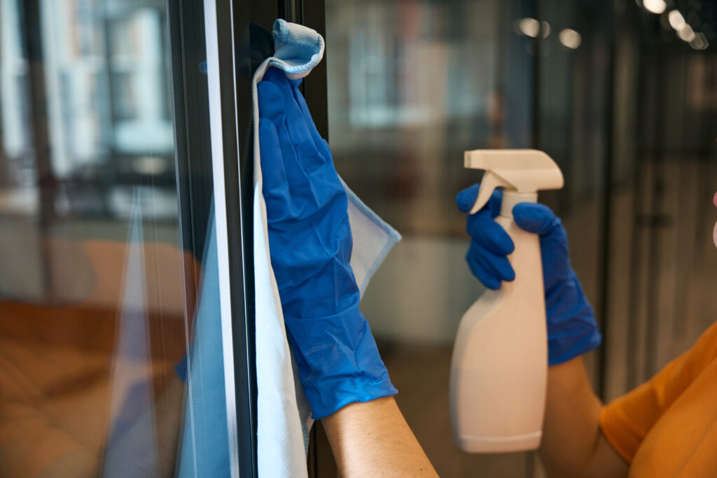 Employee of a cleaning service uses a special spray and a napkin for washing and disinfecting in the office space